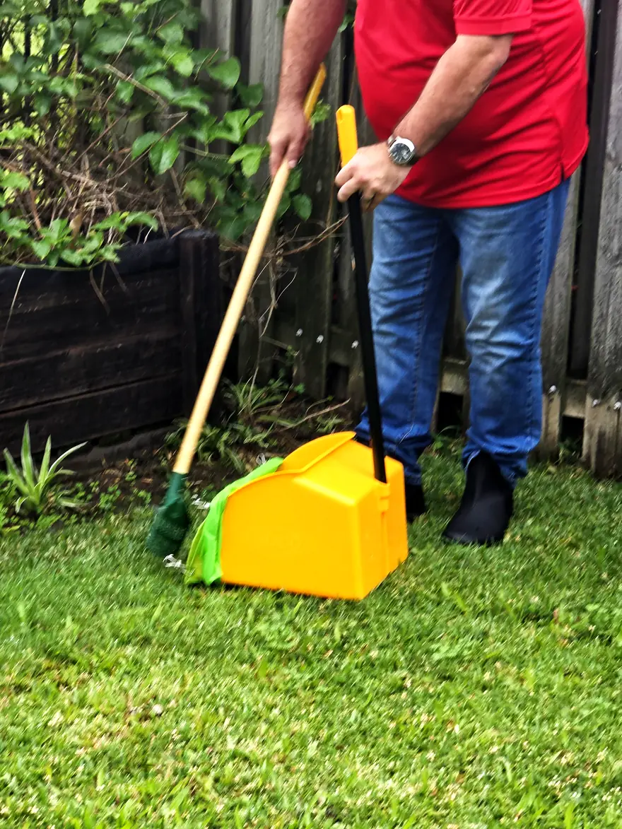 Philippe scooping dog waste from a Gold Coast lawn
